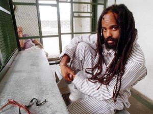 Mumia Abu-Jamal é o pseudônimo de Wesley Cook, jornalista e ex-integrante do Partido dos Panteras Negras. No início dos anos 80, foi condenado à pena de morte por supostamente matar um policial que espancava seu irmão. É conhecido no mundo inteiro pelo programa de rádio “A voz dos sem-voz”, que transmite direto da da prisão de segurança máxima SCI-Greene da Pensilvânia. - Foto:pauldavisoncrime.blogspot.com