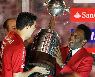 Pelé entrega a taça ao campeão em 2010, o garoto propaganda do Banco espanhol repetirá o gesto em 2011?  - Foto:sensacionalfc.wordpress.com